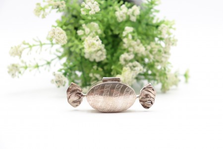 Caixa de comprimidos em prata e forma de rebuçado com bandas alternadas lisas e 